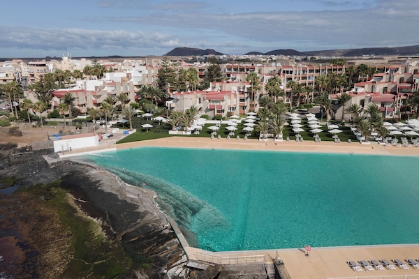 Alberca al aire libre, sombrillas en la alberca y camastros