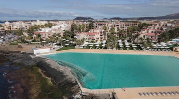Una piscina al aire libre, sombrillas, sillones reclinables de piscina