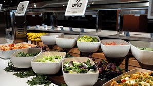 Ein Buffet mit verschiedenen Speisen, darunter Salate, Obst und Pasta.