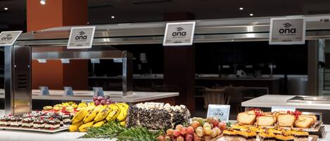 A buffet with various food items including fruits, cakes, and pastries.