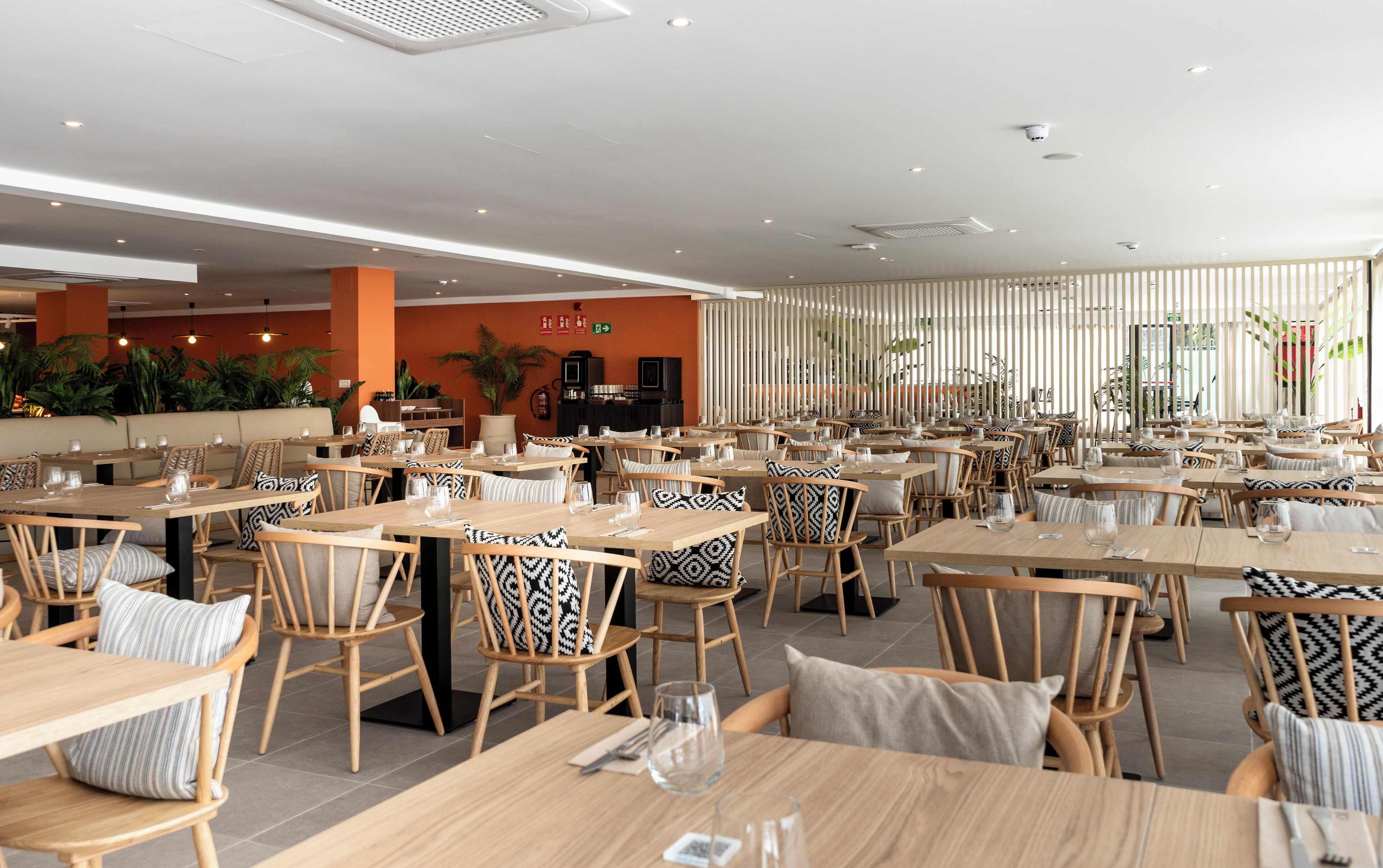 A spacious restaurant with multiple tables and chairs, a kitchen area, and a seating area with a view of the outdoors.