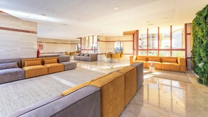Eine großzügige Lobby mit einer großen Sitzgruppe, einem Couchtisch und einer grünen Wand.