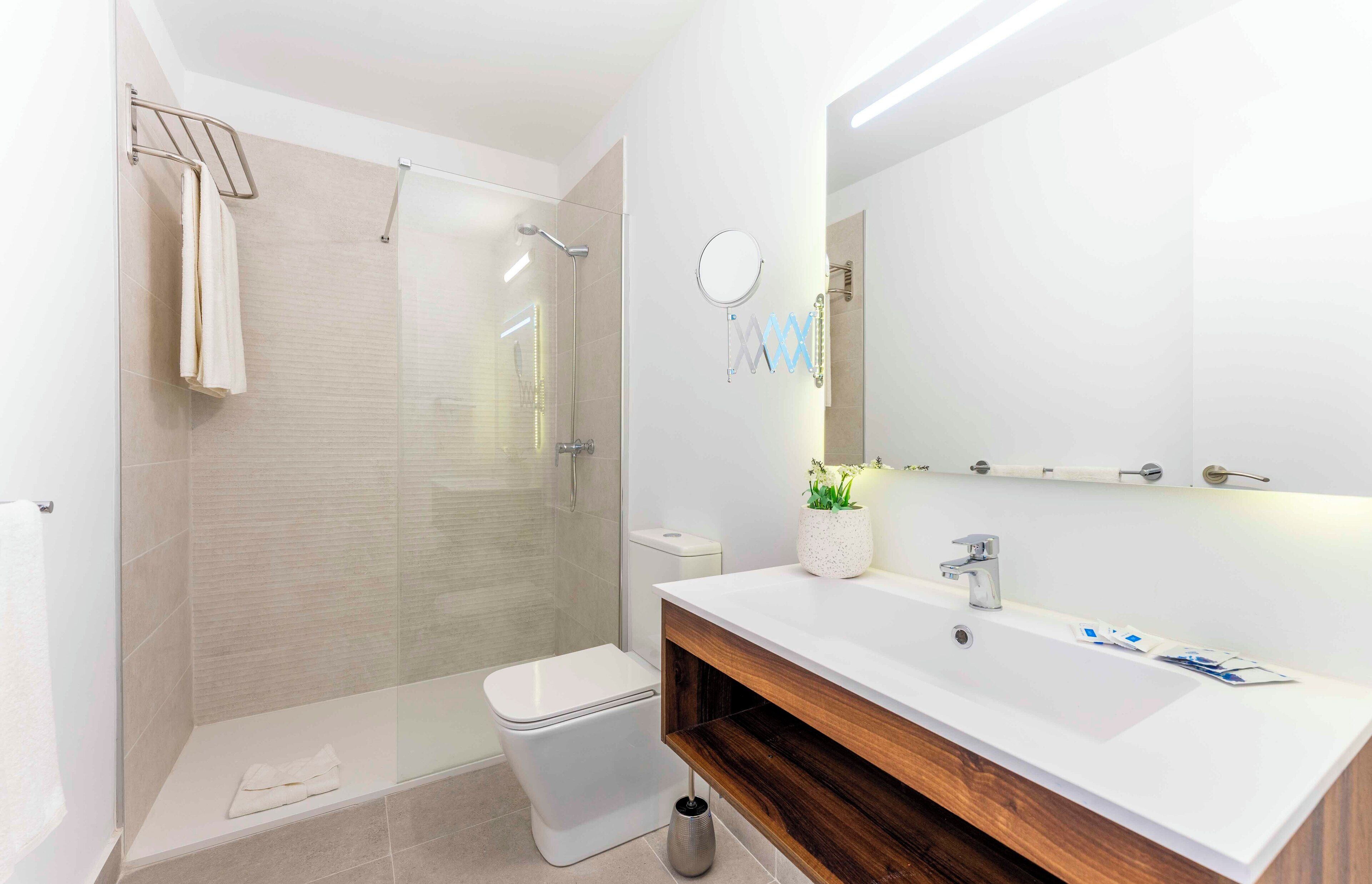 A modern bathroom with a glass-enclosed shower, a white toilet, and a vanity with a mirror and sink.