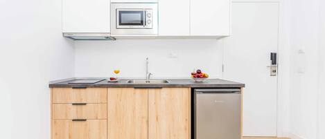 A compact kitchen with a built-in microwave, a sink, and a stainless steel dishwasher.