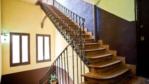 Una escalera de madera con barandilla negra que lleva a una plataforma con una planta en maceta.