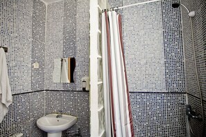 Un baño con paredes de mosaicos, un lavamanos y una cortina de ducha.
