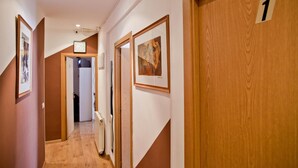 Un pasillo con puertas de madera, numeradas 1, y obras de arte enmarcadas en las paredes.