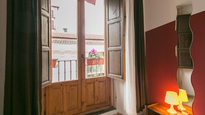 Una puerta de madera con paneles de vidrio, una mesita con dos lámparas y un espejo en la pared.