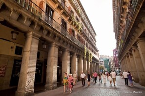 Calle histórica con edificios de arquitectura clásica, incluyendo columnas y balcones.