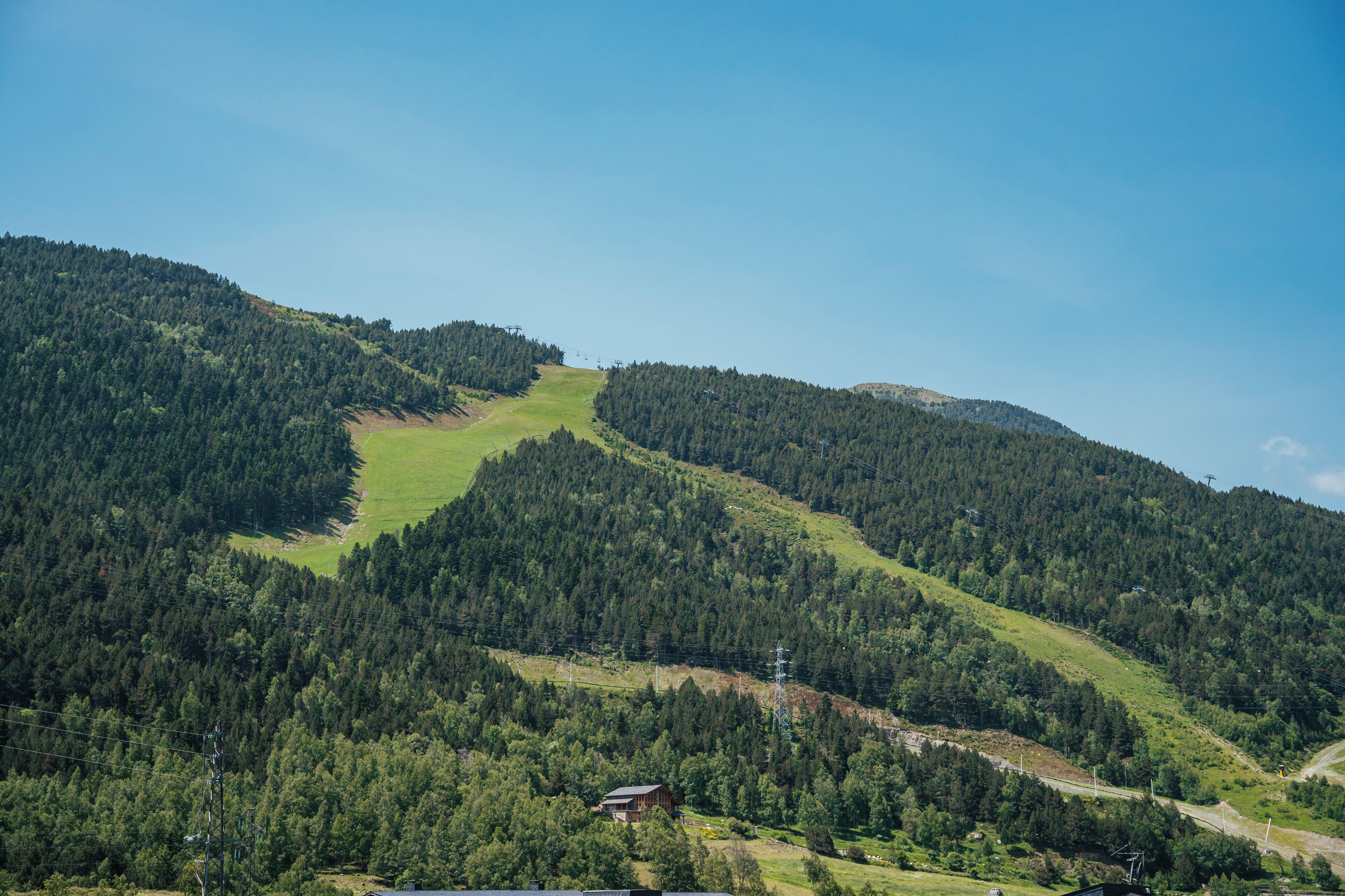 Un paysage montagneux, avec de vastes forêts et un petit chalet.