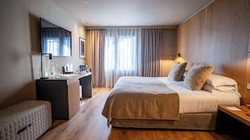 Una habitación de hotel moderna con una cama grande, un escritorio y una zona de estar.