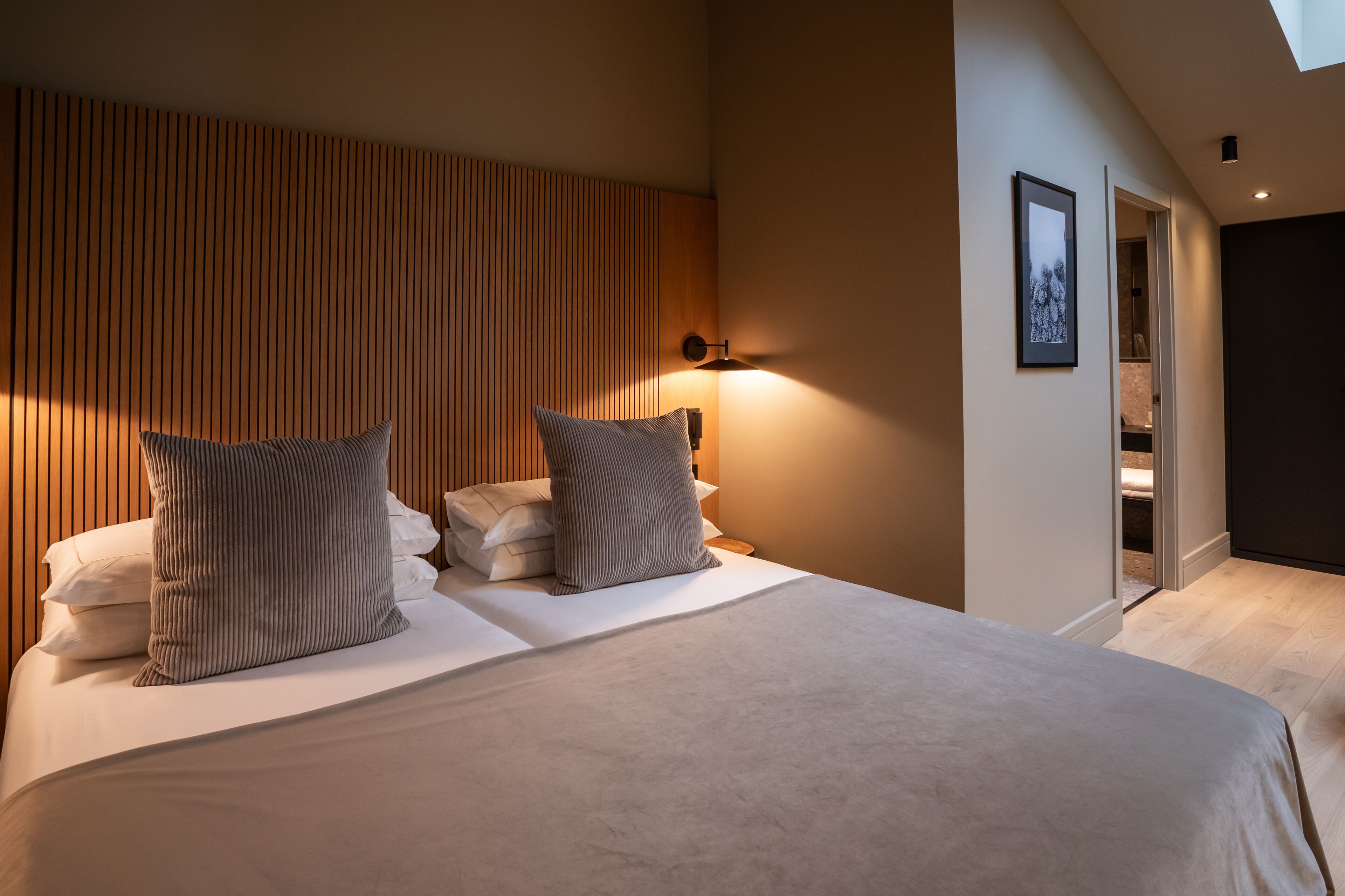 Ein modernes Schlafzimmer mit einem großen Bett, einem Holzkopfende und einem Oberlicht.