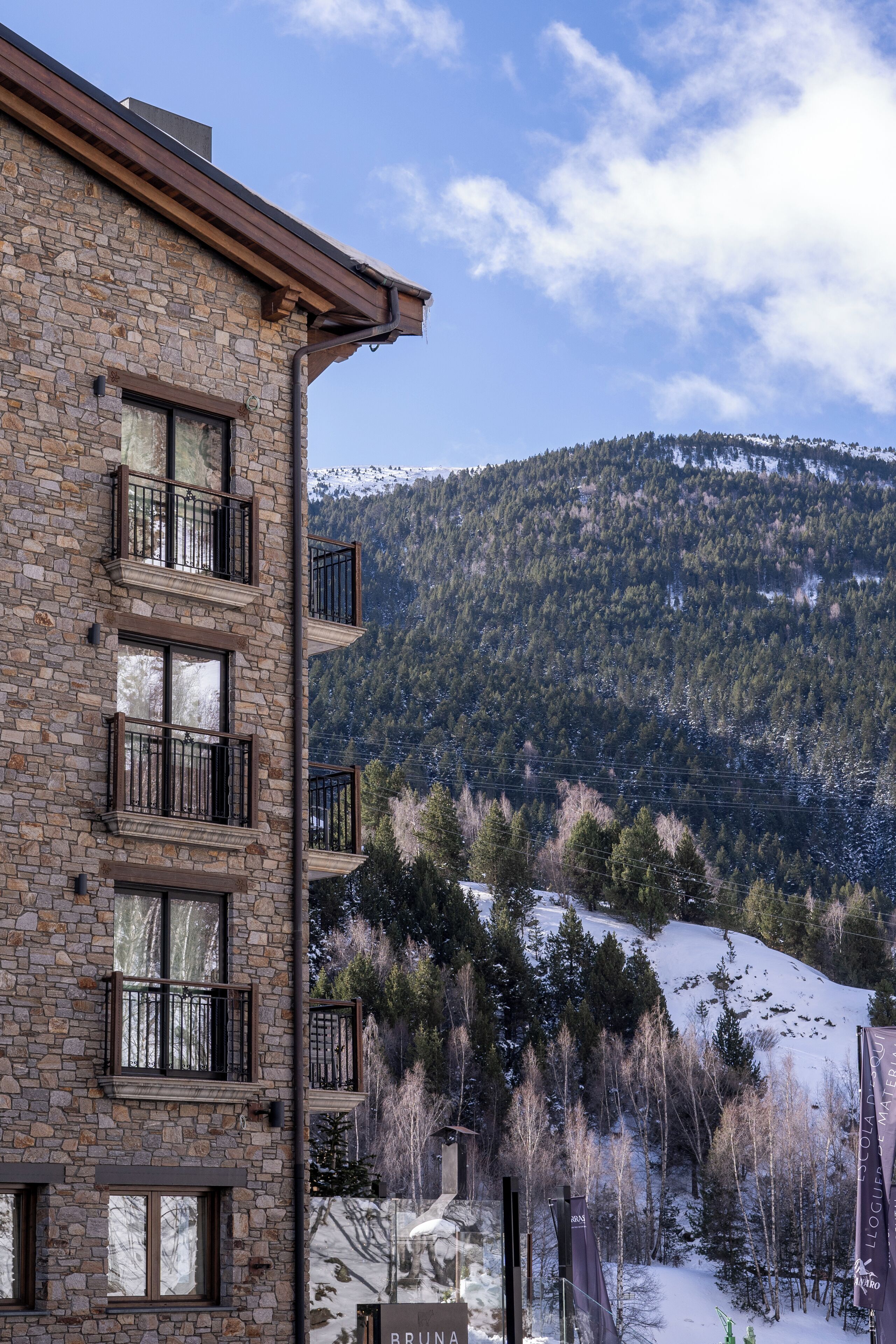 A stone building with multiple balconies and a view of a snowy mountain.