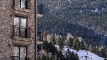 A stone building with multiple balconies and a view of a snowy mountain.