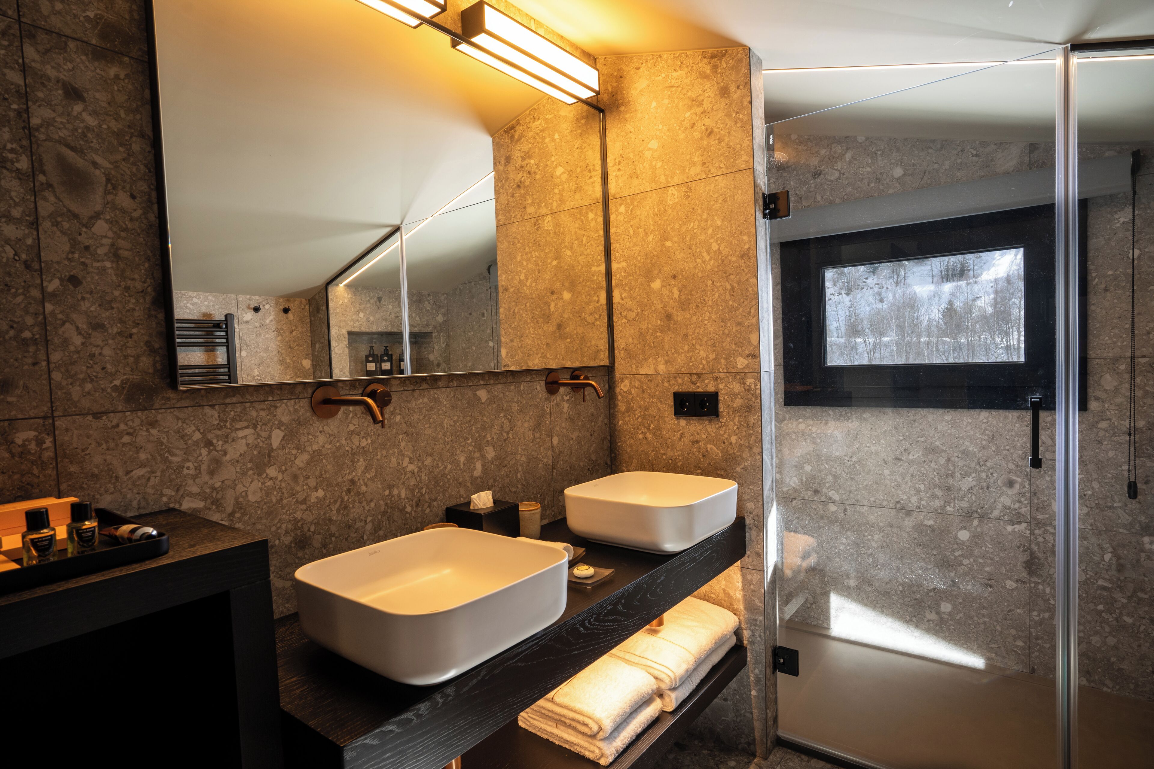 A modern bathroom with two large sinks, a large mirror, and a glass shower enclosure.