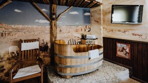 A rustic bathroom with a wooden tub, a wooden bench, and a stone floor. - Road Stop Motel Dortmund (Dortmund)