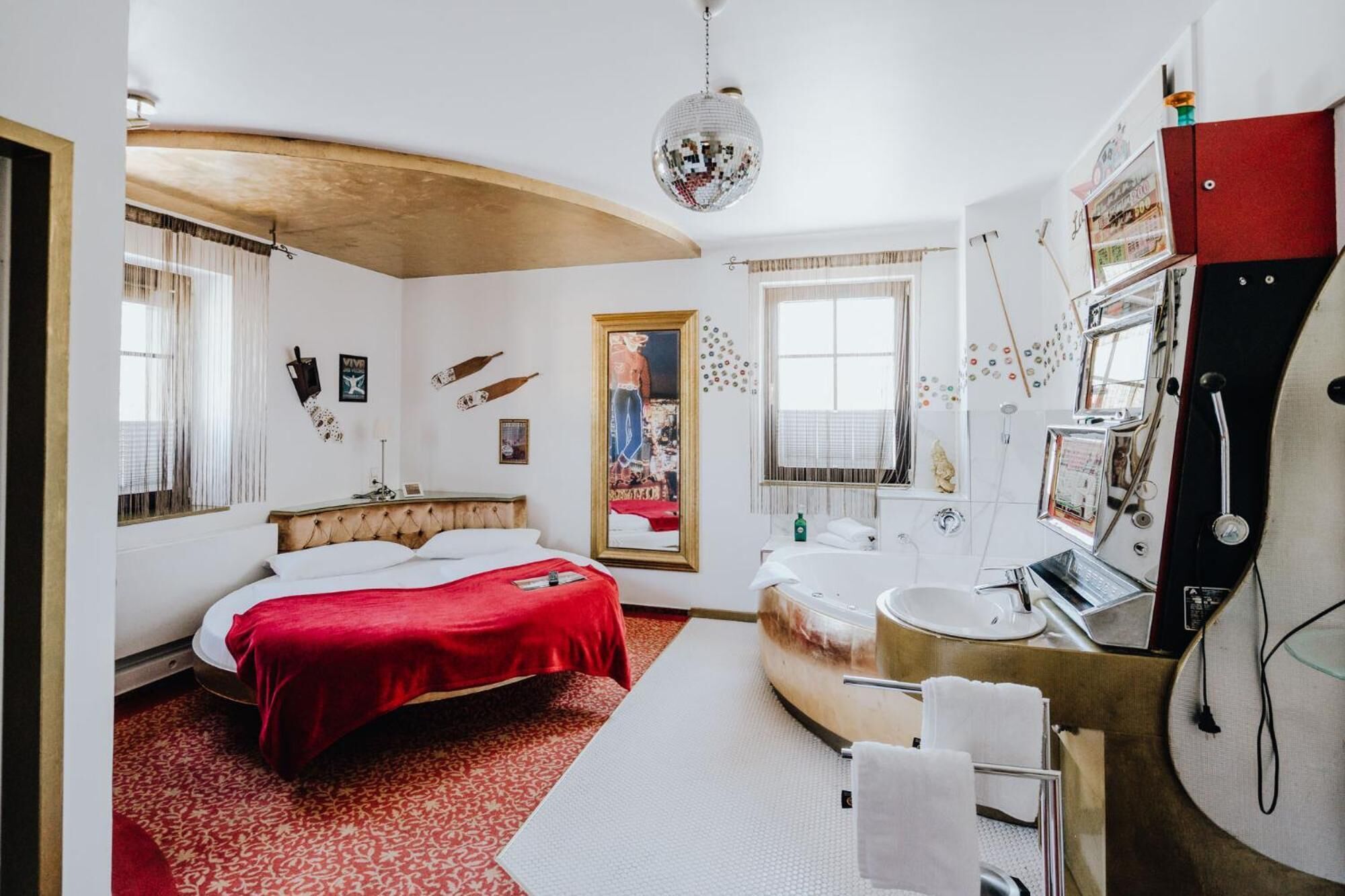 Une chambre d’hôtel moderne, dotée d’un grand lit, d’une salle de bain au design original et de divers éléments décoratifs sur les murs.