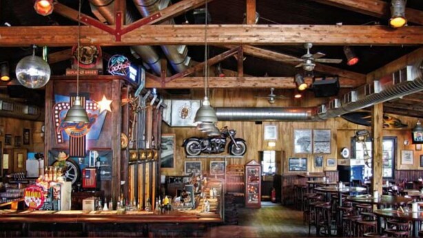 A rustic bar with wooden beams, vintage motorcycles, and neon signs. - Road Stop Motel Dortmund (Dortmund)