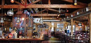 Eine rustikale Bar mit Holzbalken, historischen Motorrädern und Neonreklamen.
