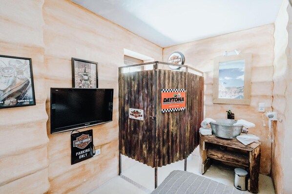 Ein Zimmer mit Motorrad-Dekor, darunter ein Harley-Davidson-Schild, ein Schild des Daytona International Speedway und ein Fernseher.