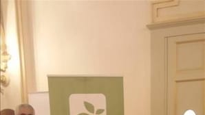 A man and a woman standing in front of a green promotional stand with an apple logo and text. - Melo Accommodations (Bari)