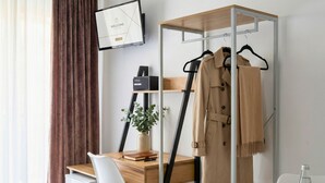 A modern hotel room with a desk, a chair, a bed, a wardrobe, and a small table with glasses and a bottle. - Melo Accommodations (Bari)