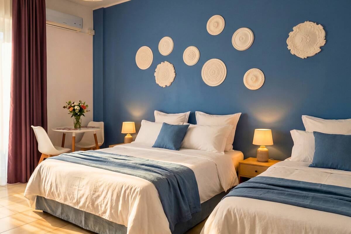 A hotel room with two beds, a dining table, and decorative wall plates.