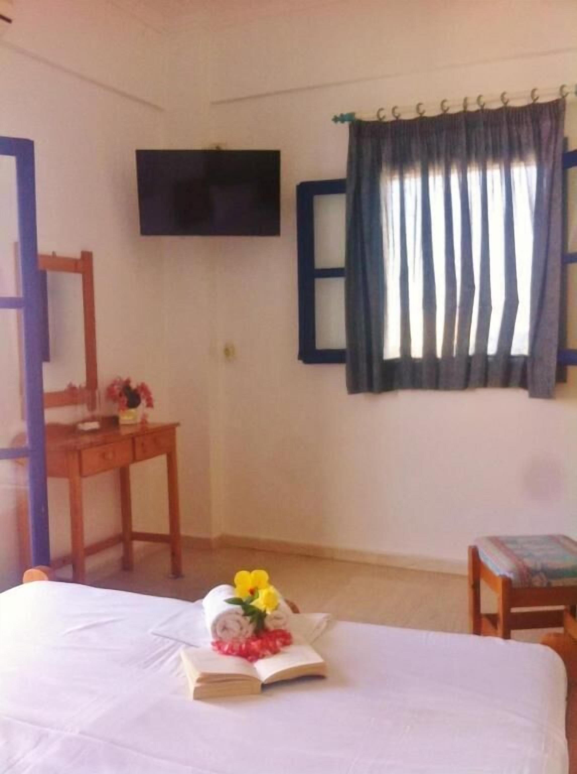 Une chambre d’hôtel équipée d’un lit, d’un bureau, d’une chaise, d’une télévision et d’une fenêtre avec des rideaux.