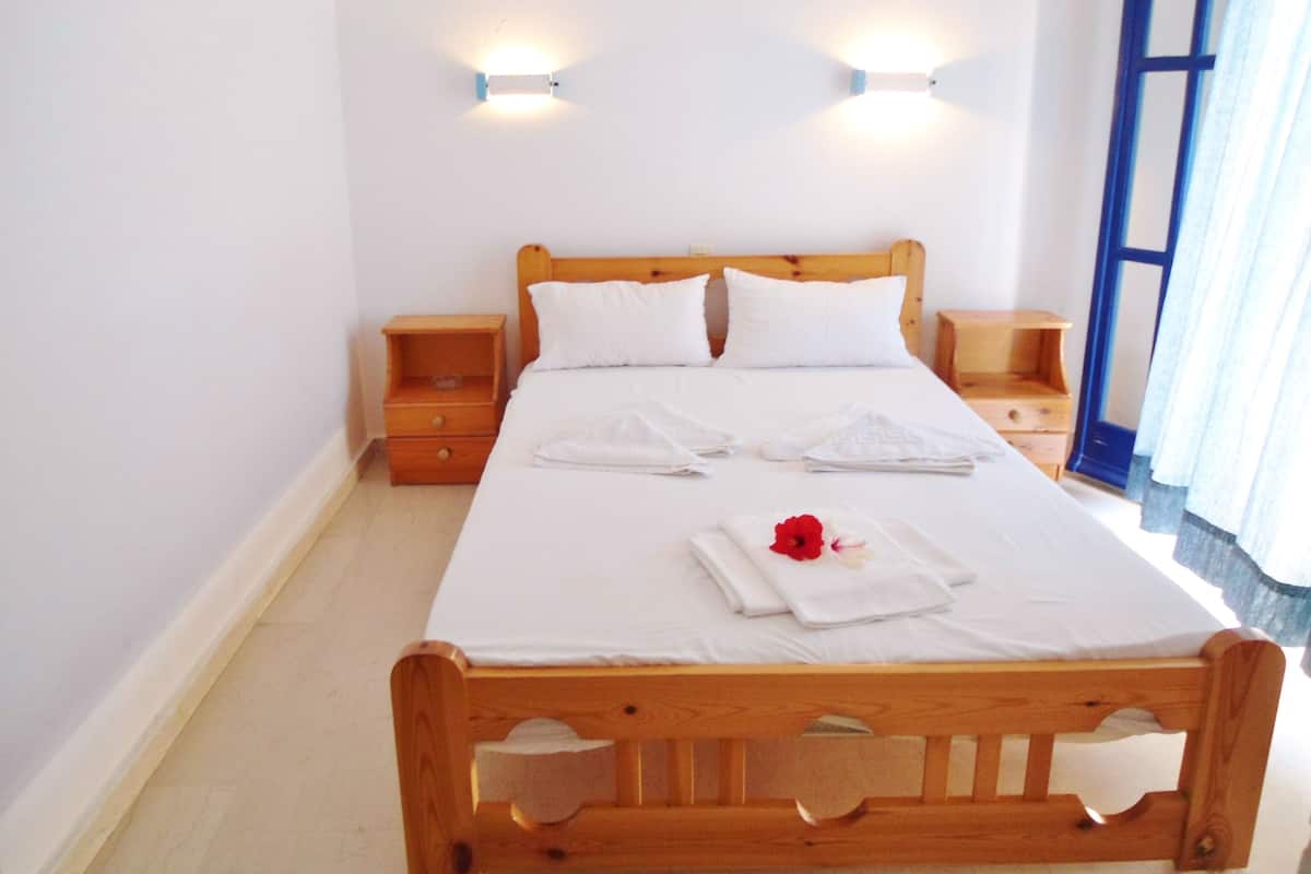 A neatly made bed with white linens, two bedside tables, and wall-mounted lights.