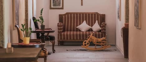 Un interior con un sofá, un caballito de madera y una cruz en la pared.