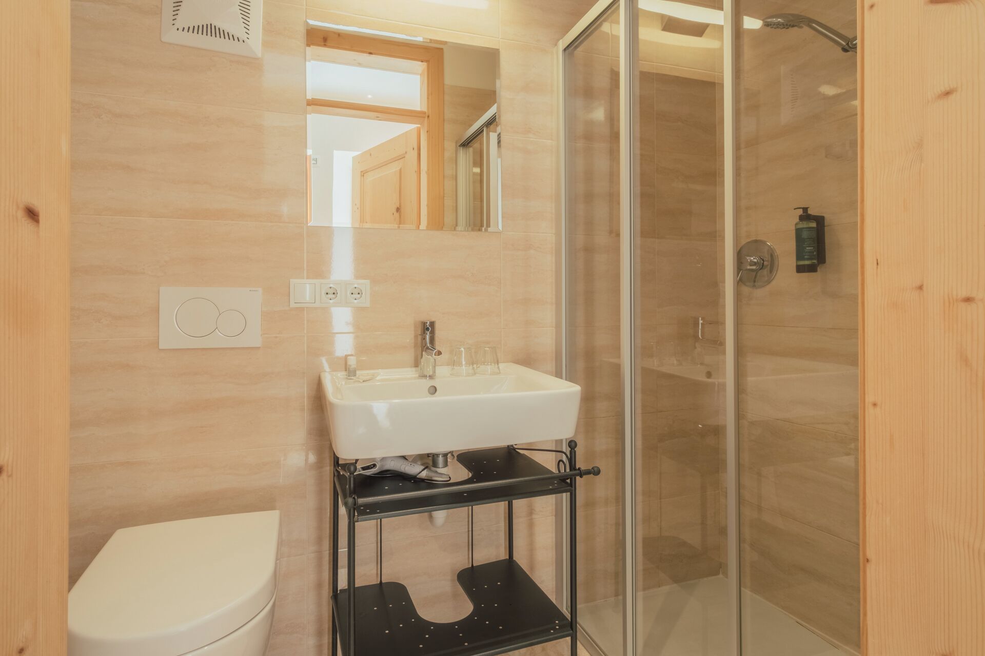 A modern bathroom with a white sink, a toilet, and a glass-enclosed shower.