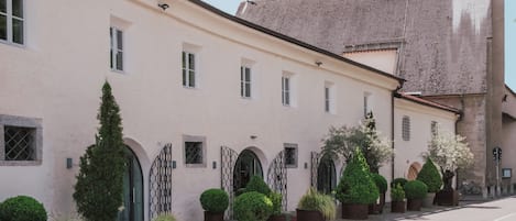 Un edificio con una fachada larga y recta, una entrada central con una reja y una torre con cúpula.