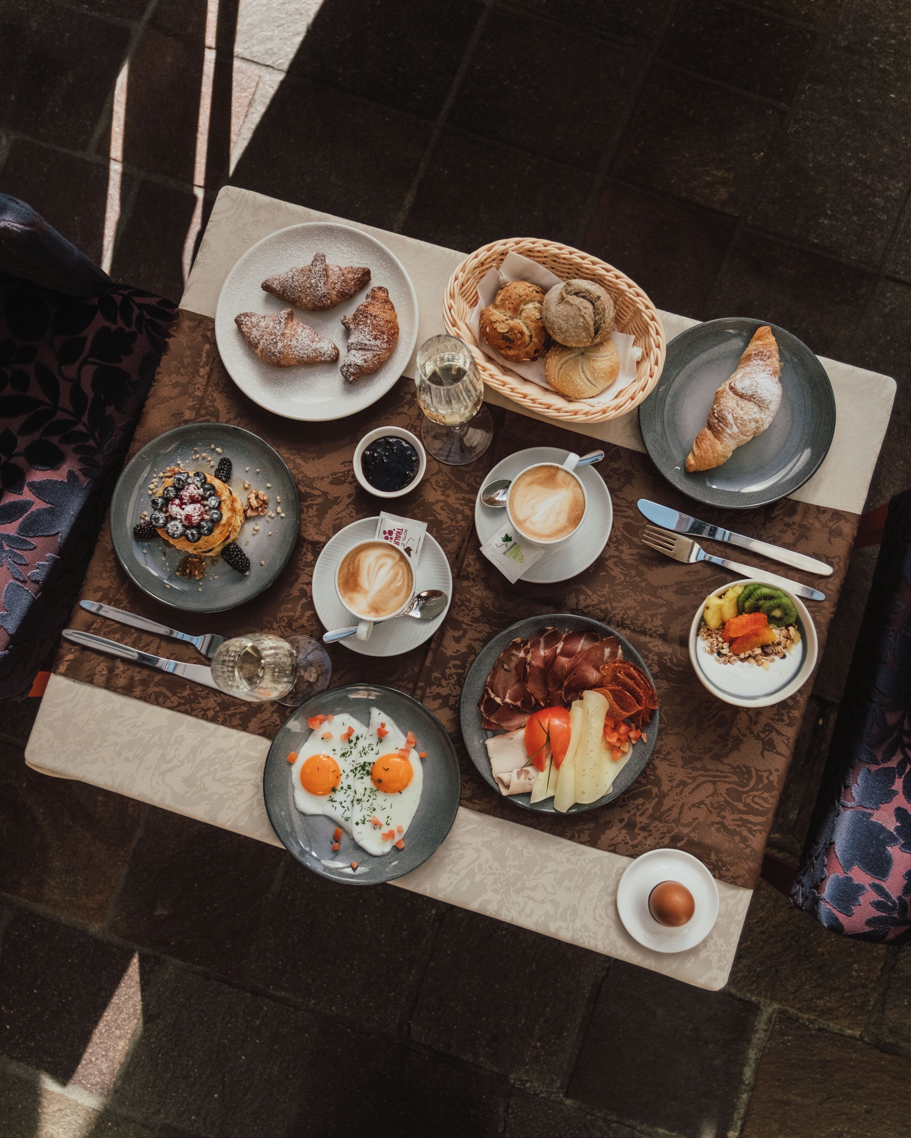 Un ambient de petit esmorzar amb diversos plats, un cistell de pa i una tassa de cafè damunt d'una taula.