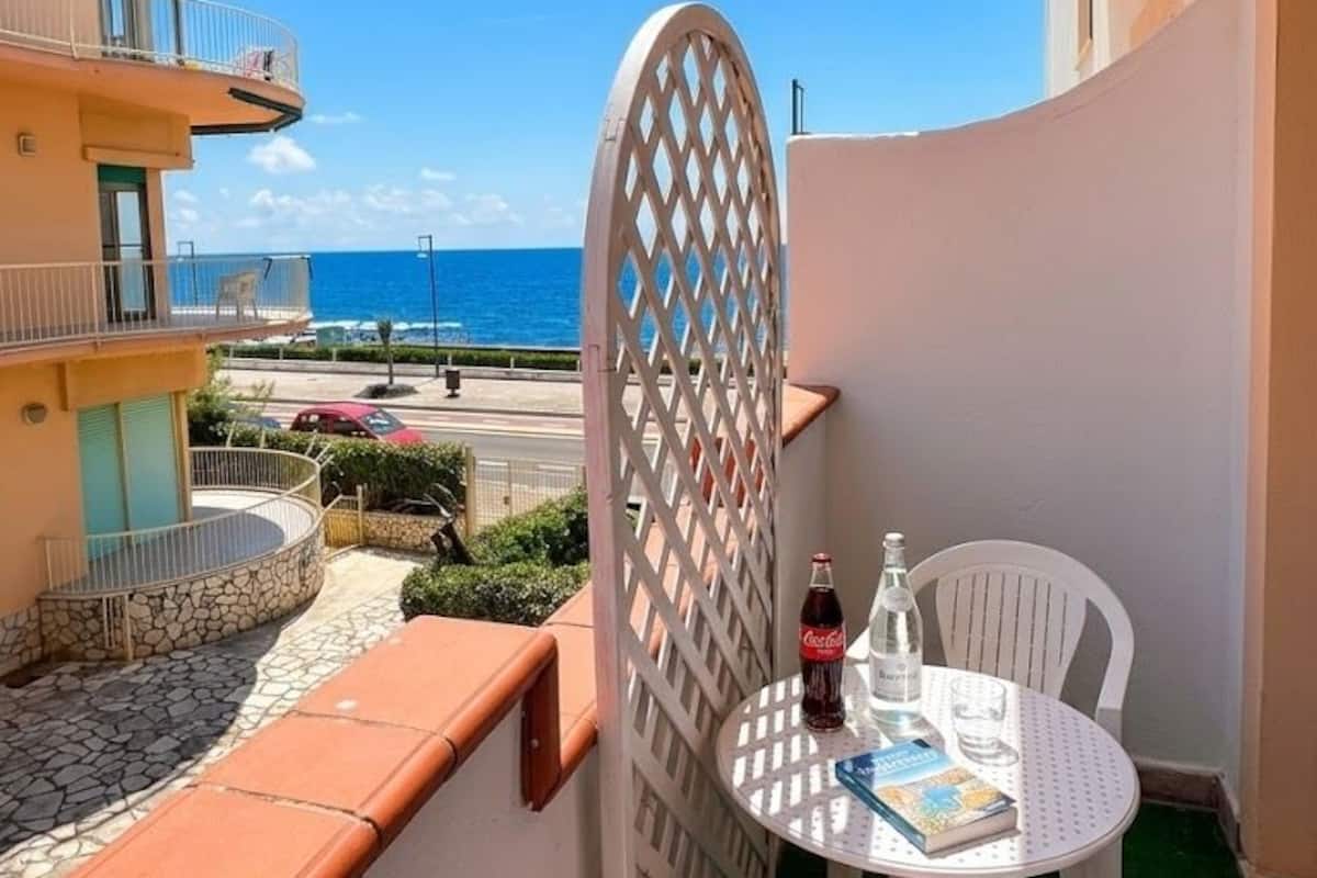 Un balcón con una mesa, sillas y una botella de Coca-Cola.