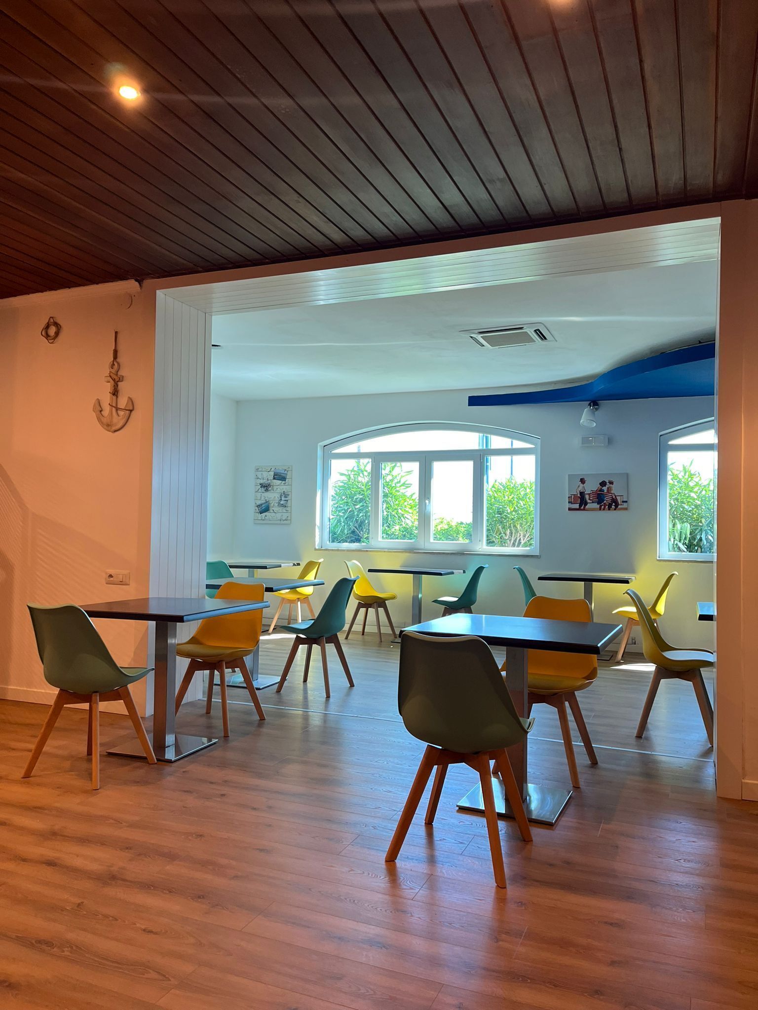Un'aula moderna con pavimento in legno, sedie colorate e ampie finestre.