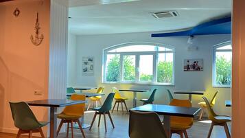 A modern classroom with wooden floors, colorful chairs, and large windows.