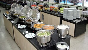 A buffet setup with various food items and stacked plates. - Taiyo Thermas Hotel (Caldas Novas)