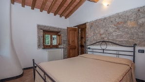 A bedroom with a stone wall, a wooden door, a window, and a bed with a metal frame. - Agriturismo Golfo dei Poeti Fattorie Bedogni Von Berger (La Spezia)