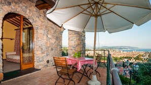 A stone balcony with a table and chairs, a large umbrella, and a view of a cityscape. - Agriturismo Golfo dei Poeti Fattorie Bedogni Von Berger (La Spezia)