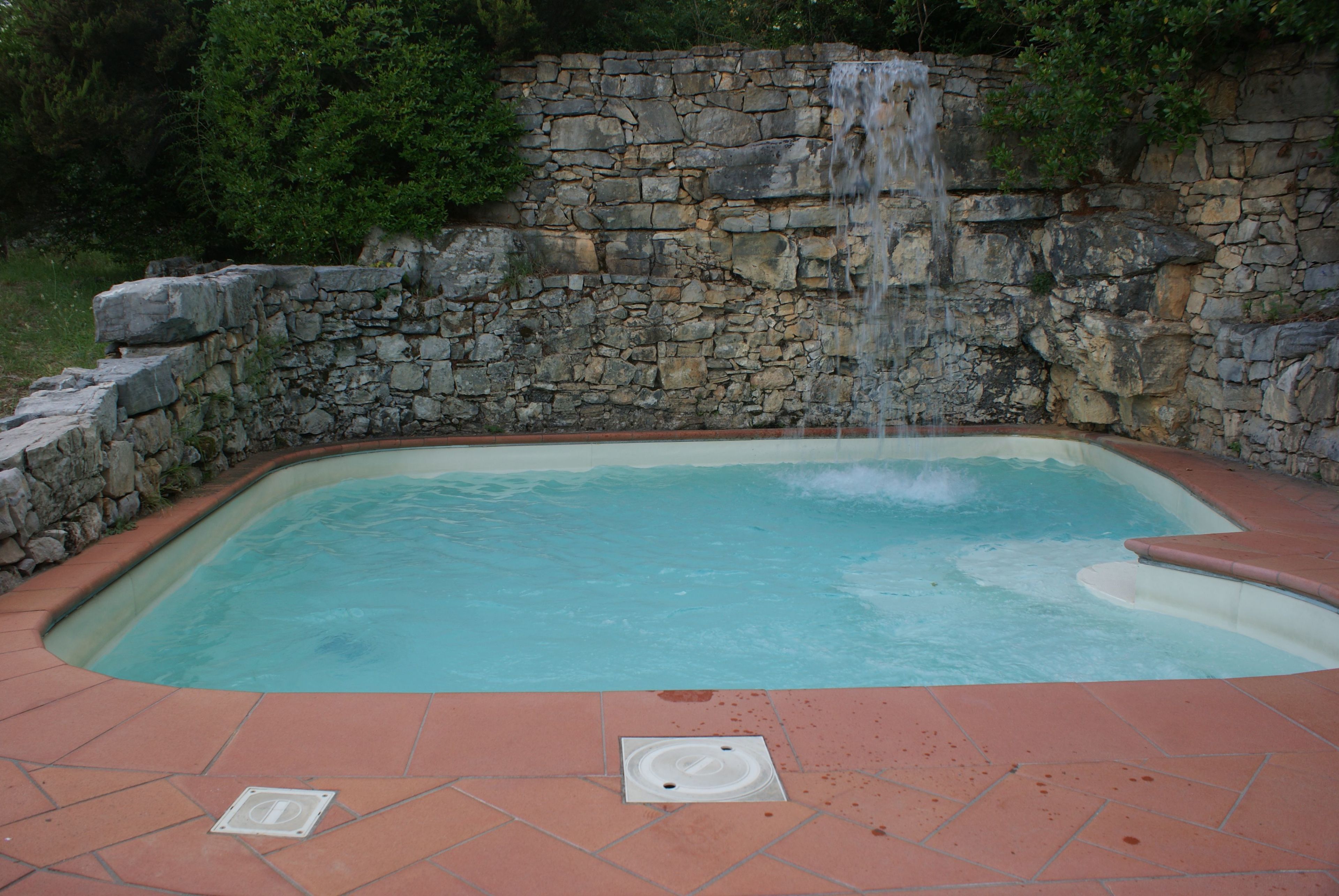 Ein Whirlpool mit Steinwand und Wasserfall.