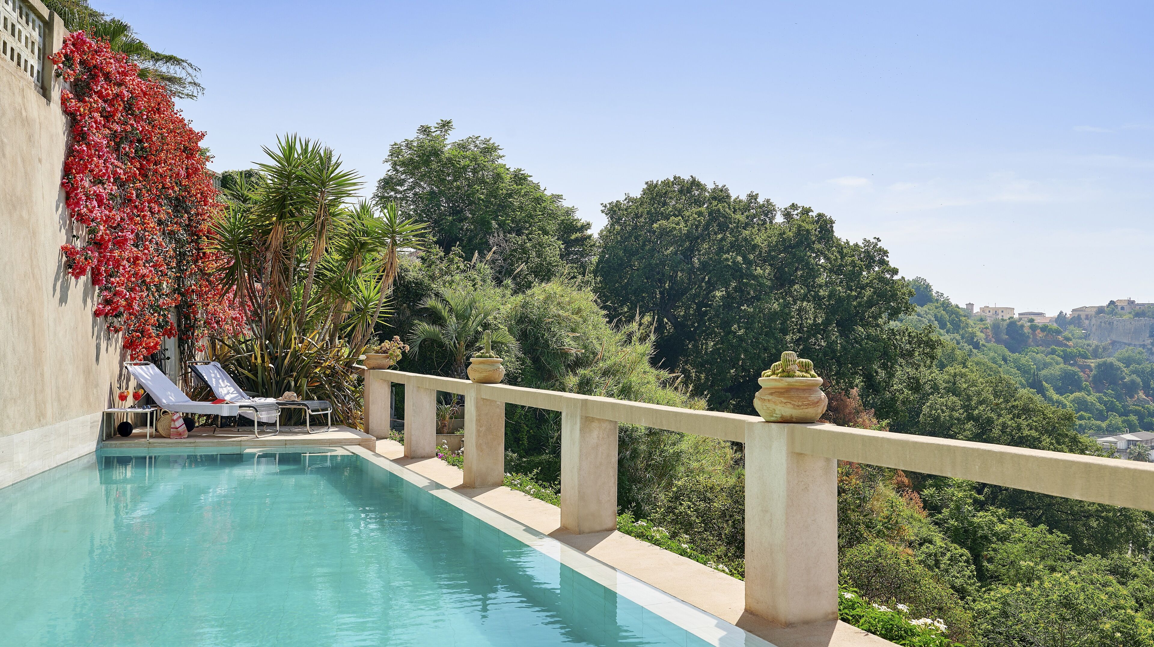 Una piscina con vista a exuberante vegetación y edificios a lo lejos.