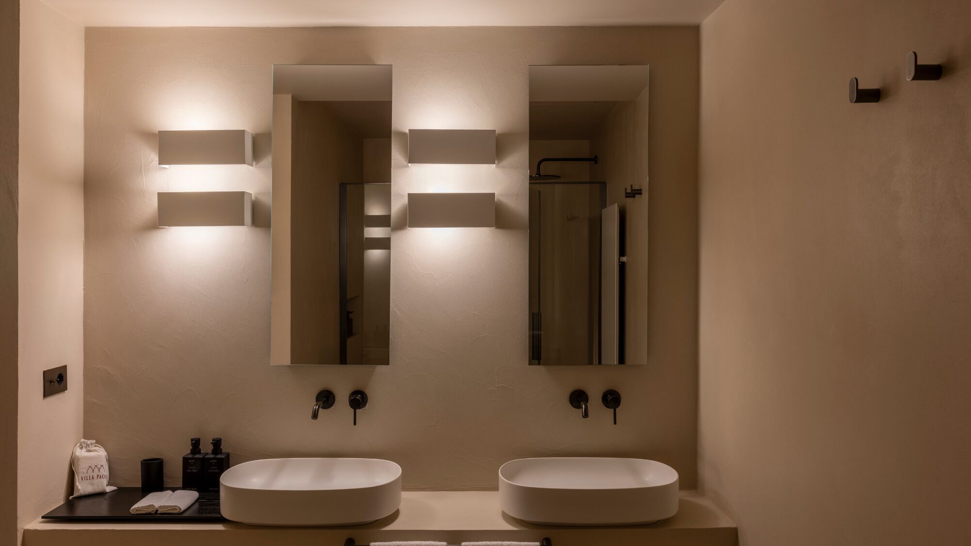 A bathroom with two sinks, a mirror, and wall-mounted lighting.