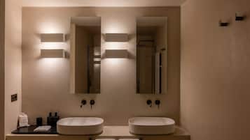 A bathroom with two sinks, a mirror, and wall-mounted lighting.