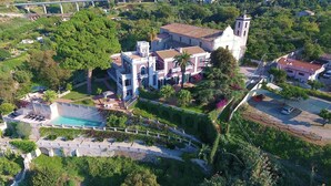 An aerial view of a large estate with a swimming pool, lush gardens, and a prominent building with a bell tower. - Villa Paola (Tropea)