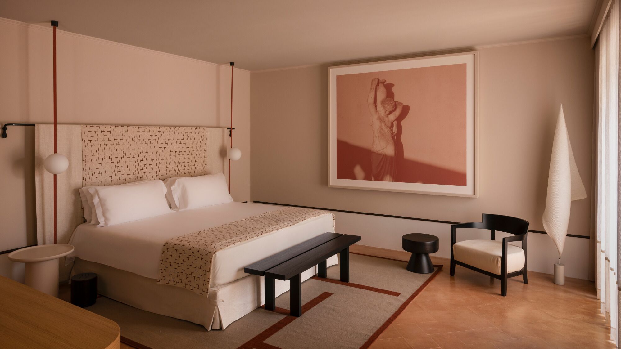 Une chambre à coucher moderne, avec un lit, une table de chevet, une chaise et une grande œuvre d’art encadrée accrochée au mur.