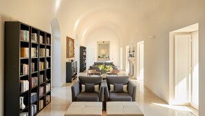 A spacious living room with a high ceiling, a fireplace, and a bookshelf filled with books. - Villa Paola (Tropea)