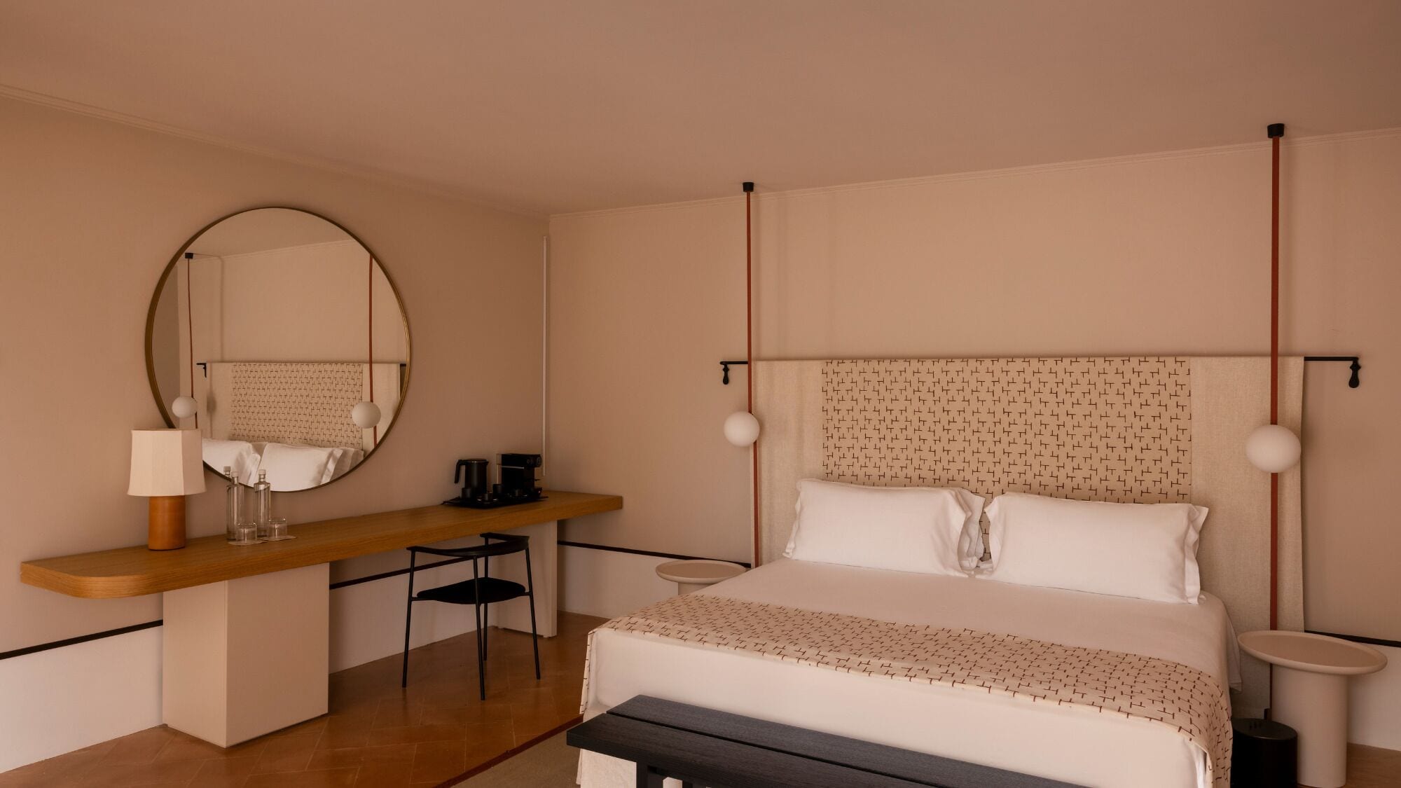 A hotel room with a bed, bedside table, chair, and a large mirror.