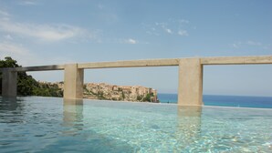 A clear swimming pool with a view of a coastal town and a cliff. - Villa Paola (Tropea)