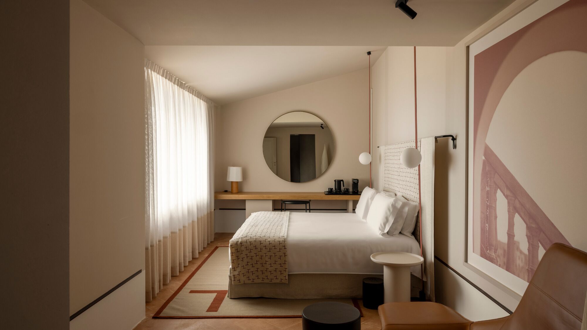 Una camera d'albergo con un letto, un comodino, una lampada e un grande specchio.