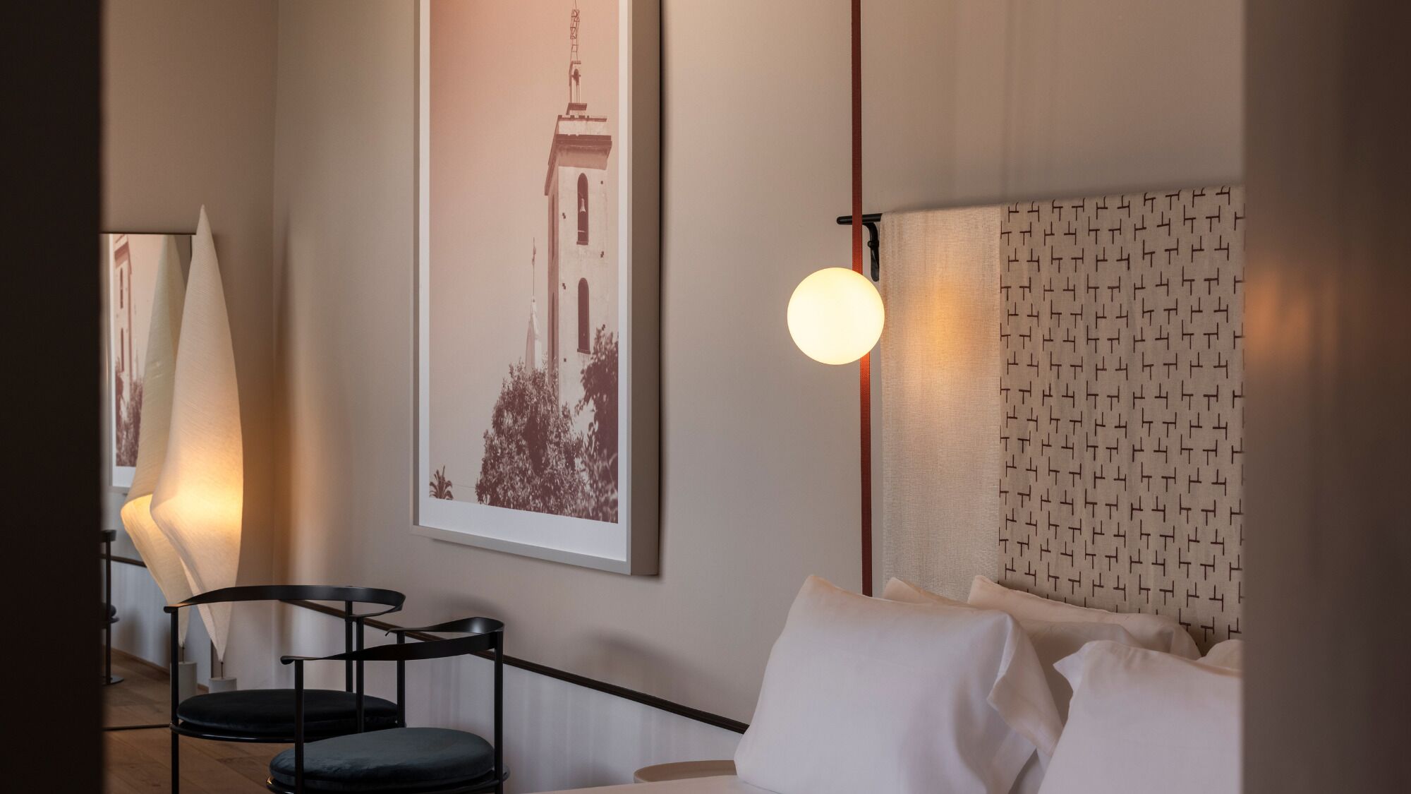 Une chambre d’hôtel avec un lit, un tableau encadré au mur, une lampe et une petite table avec des chaises.